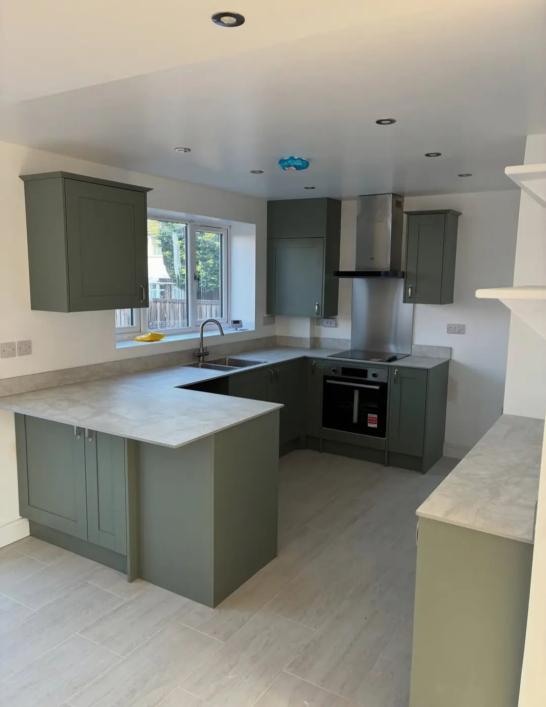 Sage green kitchen installation with grey worktops