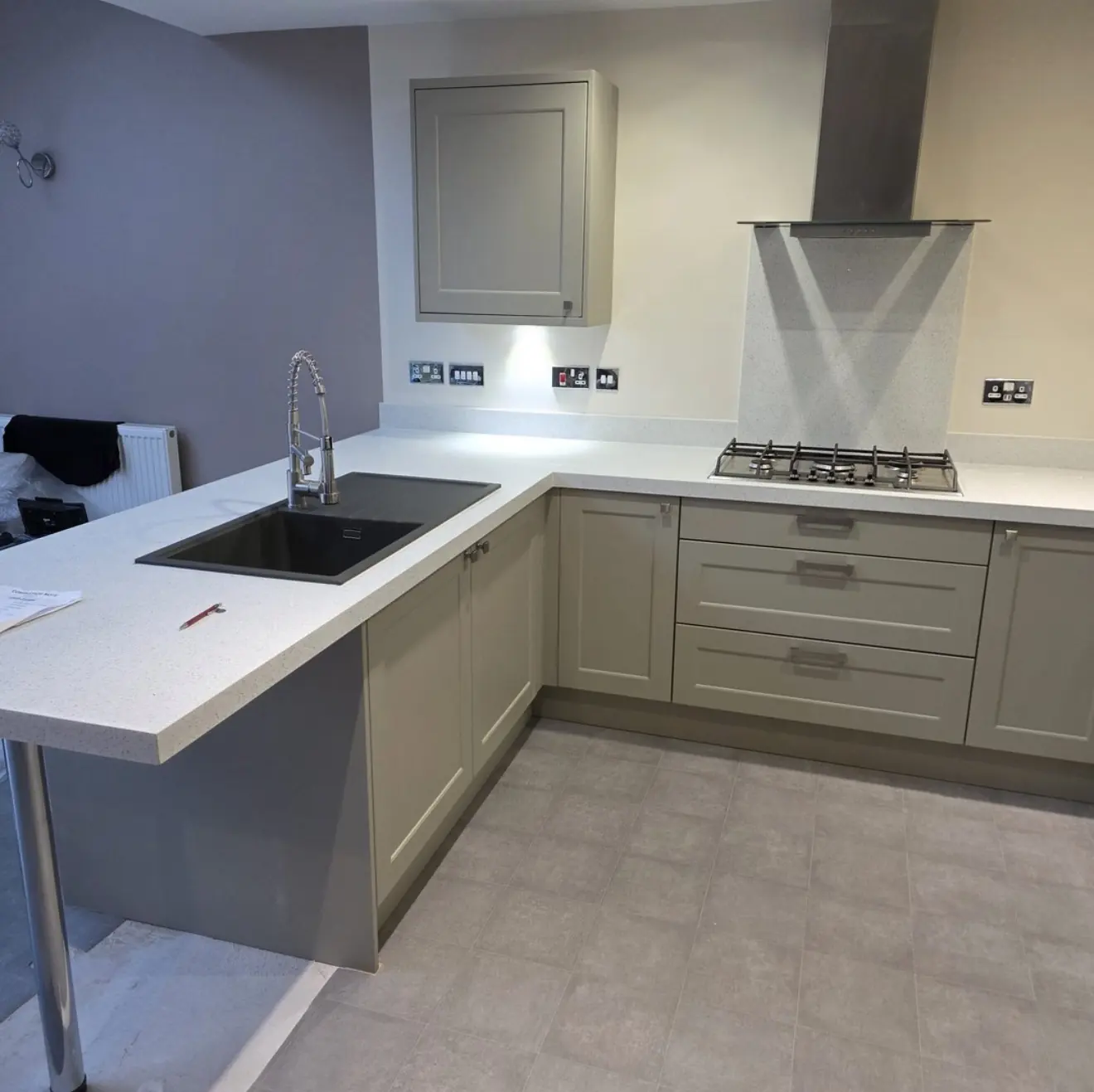 Light grey shaker kitchen with white worktop and breakfast peninsula