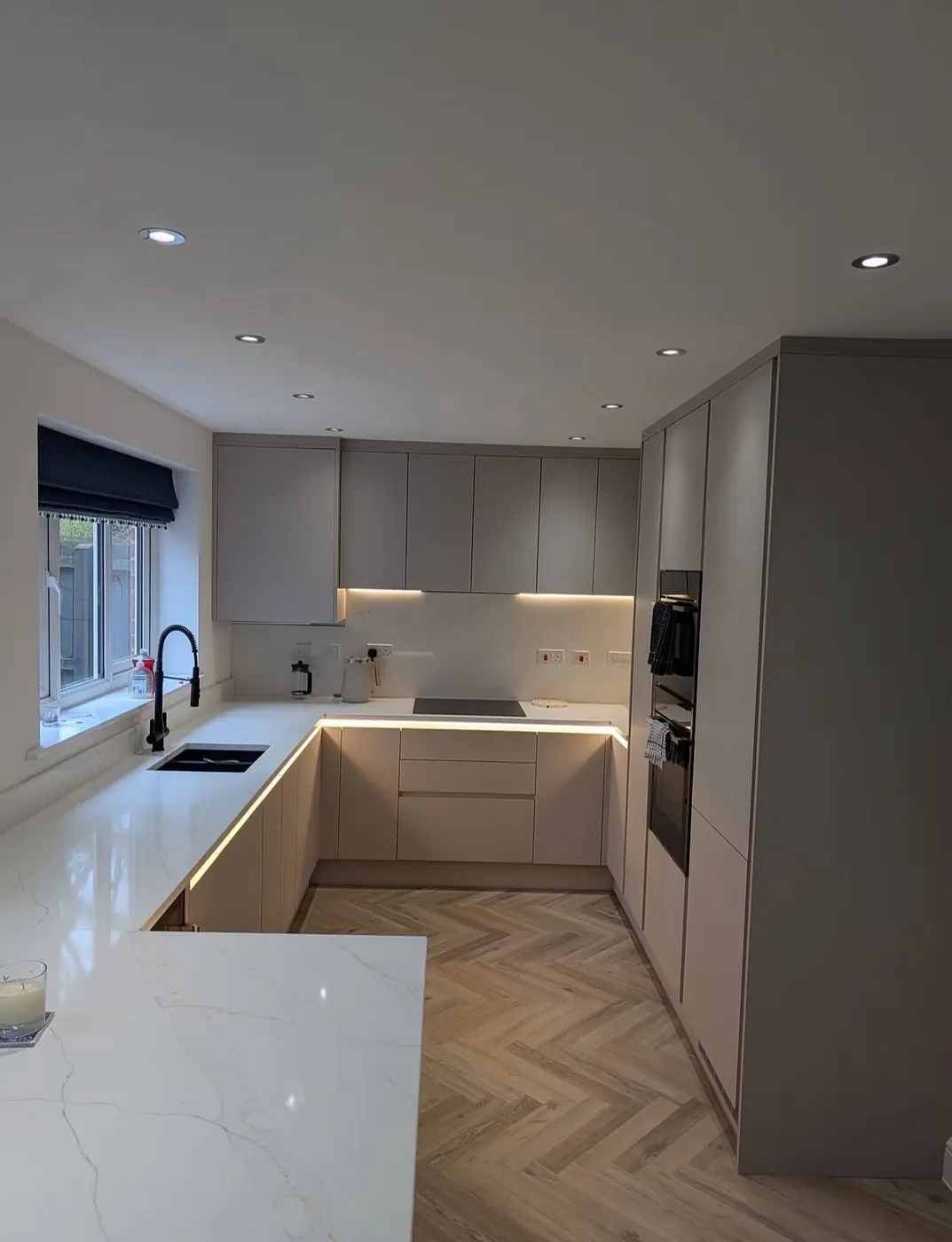 Cashmere handleless kitchen with under-cabinet lighting and quartz worktops