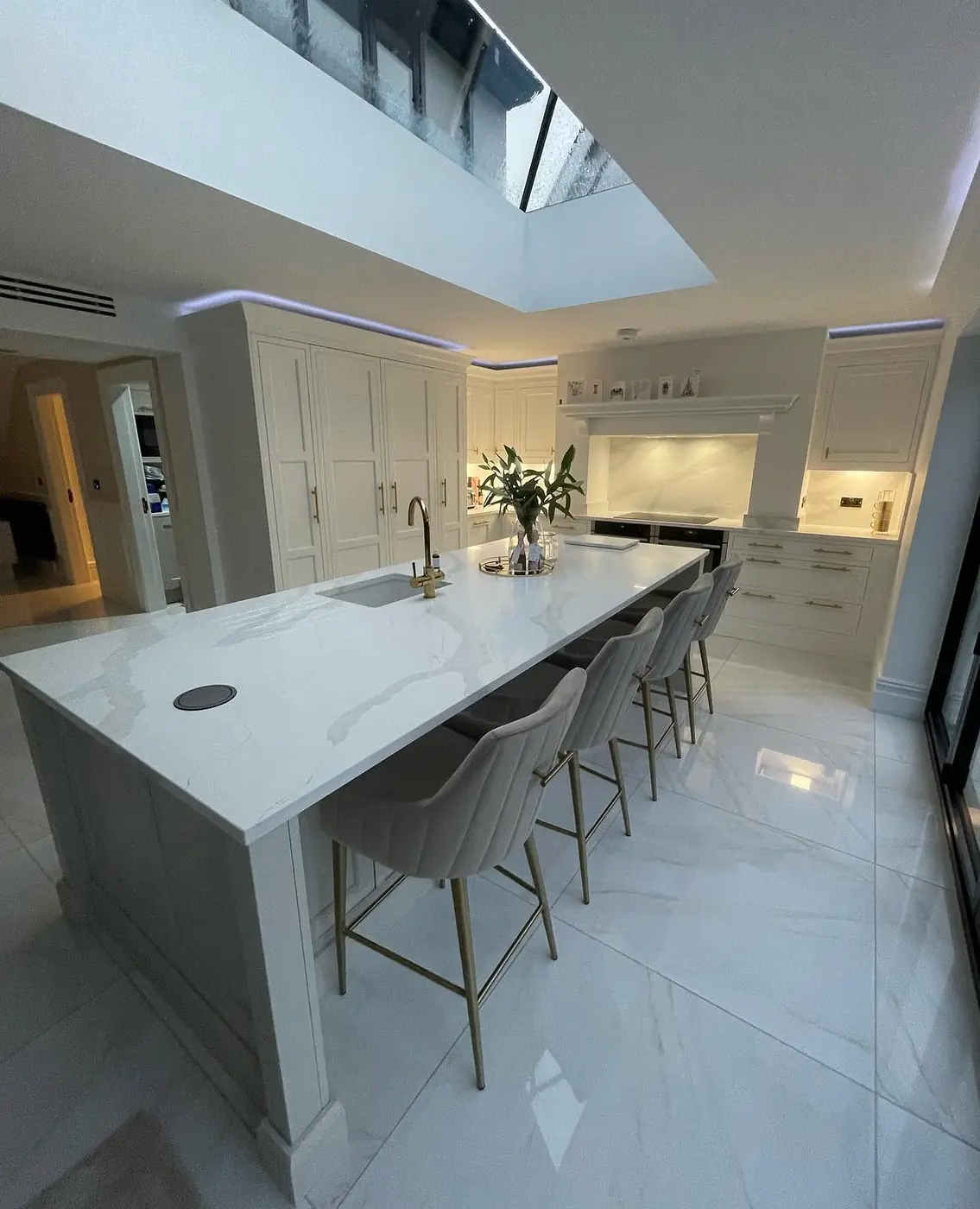 Large kitchen island with white quartz worktop under a roof lantern